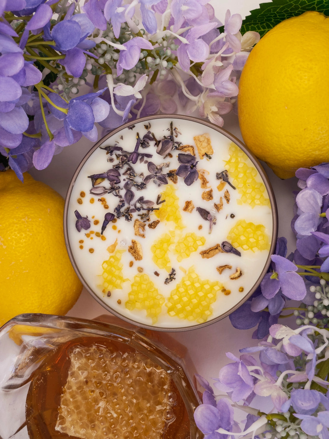 Candle with honeycomb, lavender flowers, and lemons on a white background
