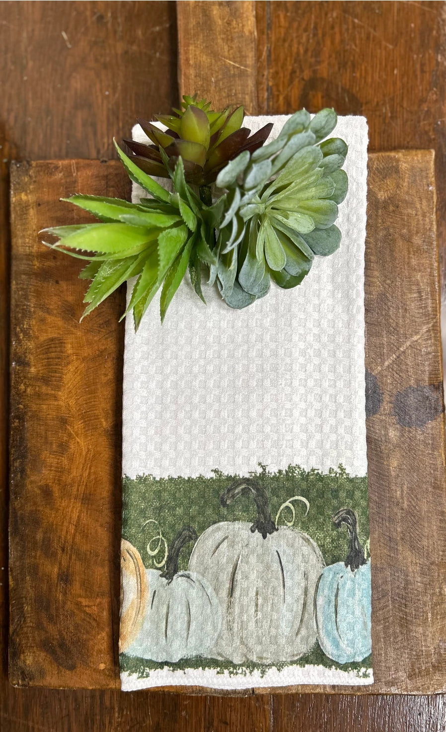 Decorative towel with pumpkins and succulents on a wooden surface