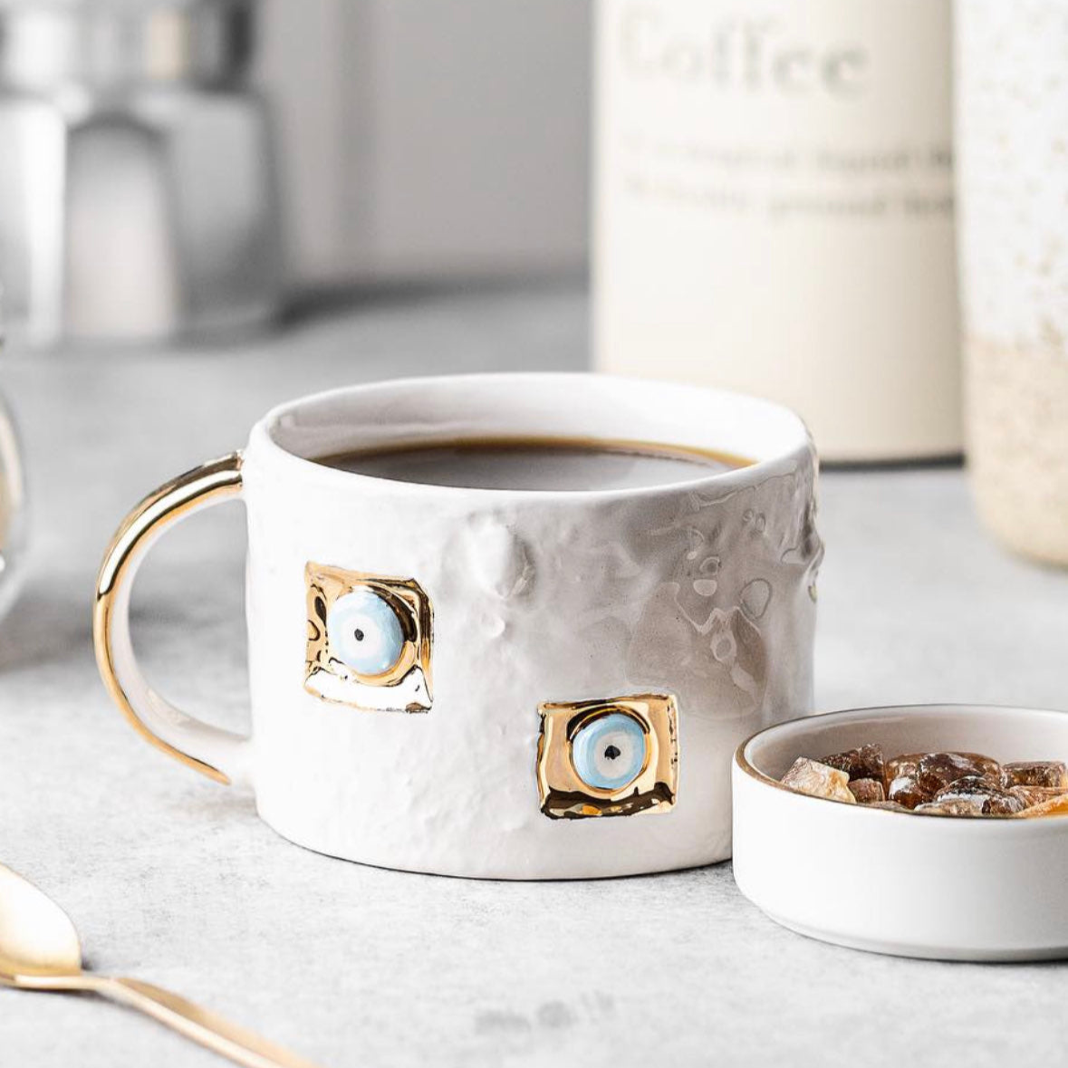 White mug with gold accents and decorative elements on a light surface.