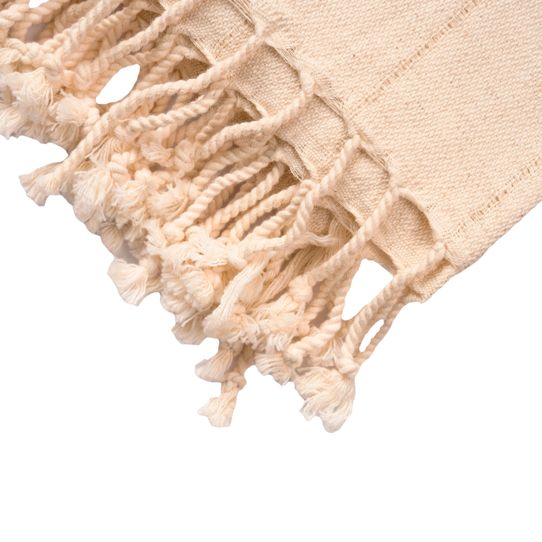 Close-up of a beige towel with tassels on a white background