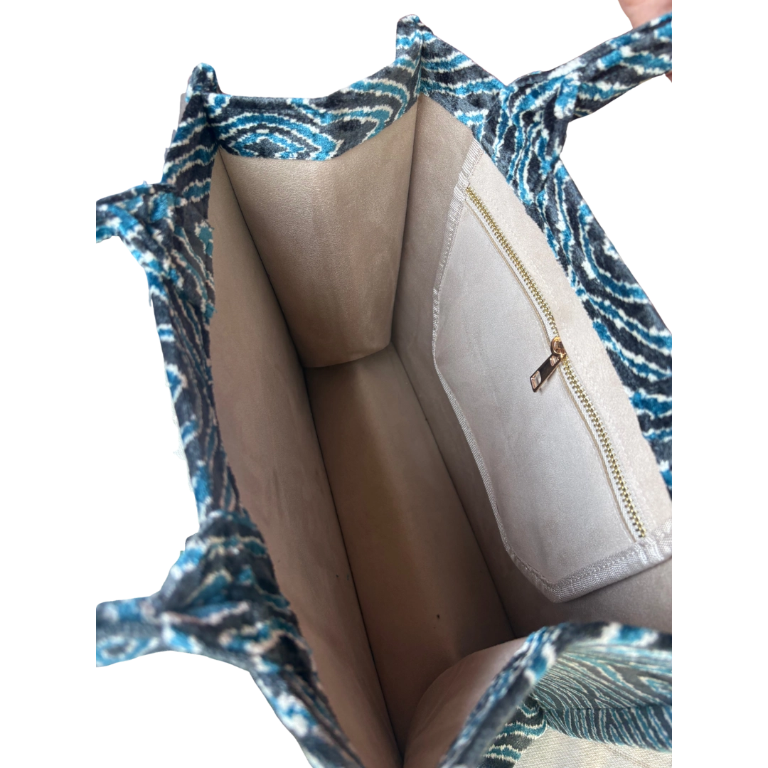Open handbag with blue and white patterned exterior and beige interior.