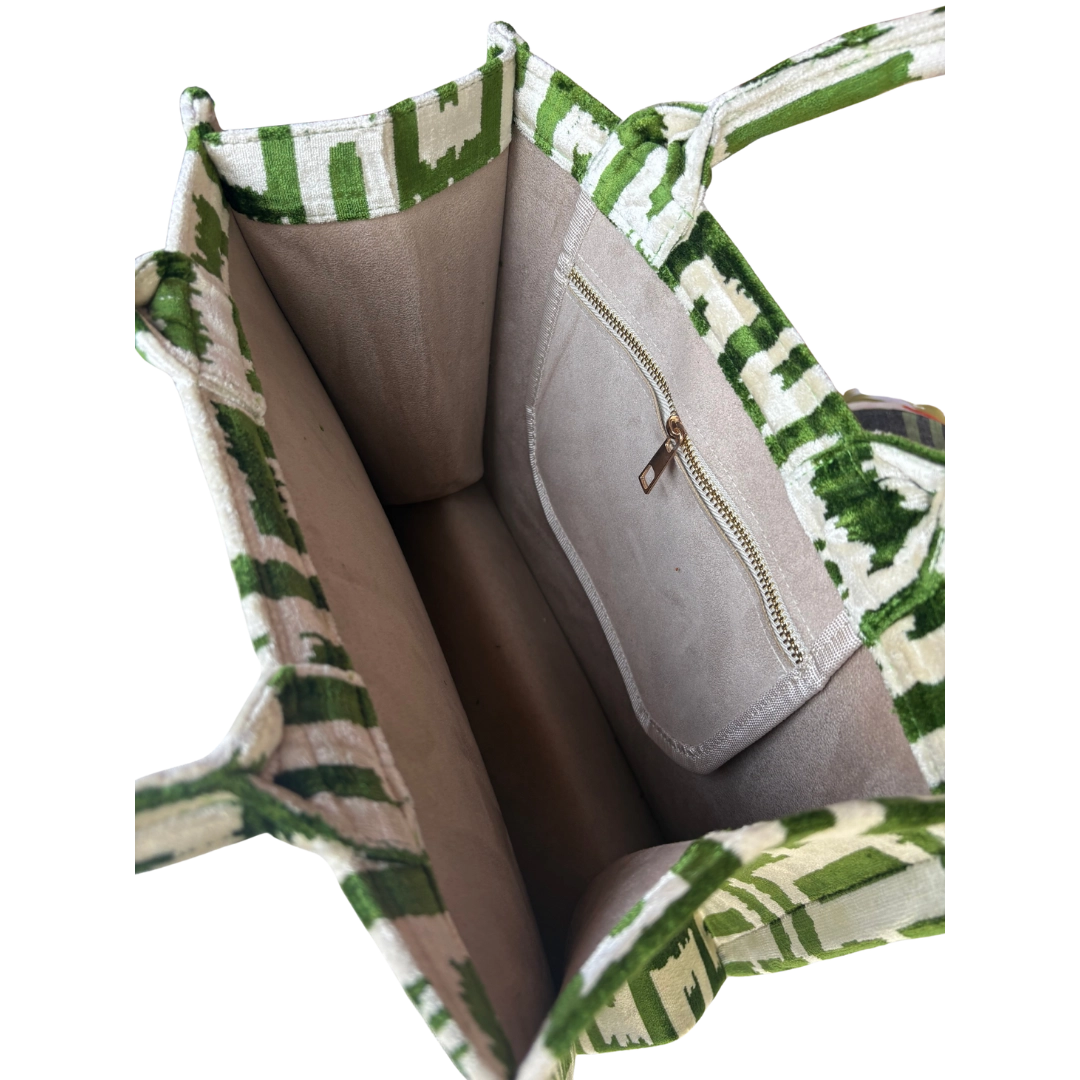 Open handbag with green and white patterned handle and interior.