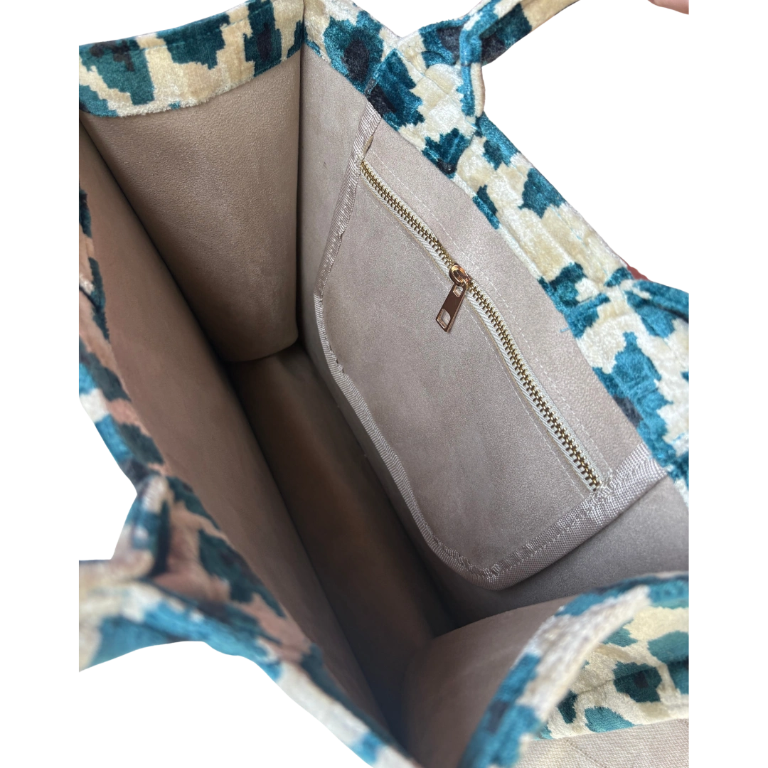 Close-up of a handbag with a patterned flap and zipper pocket.