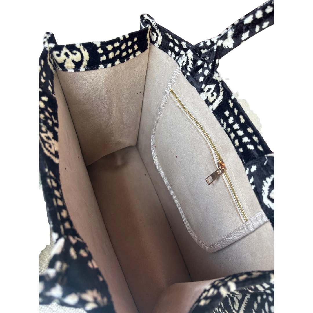 Black and white patterned bag with a gold zipper on a white background