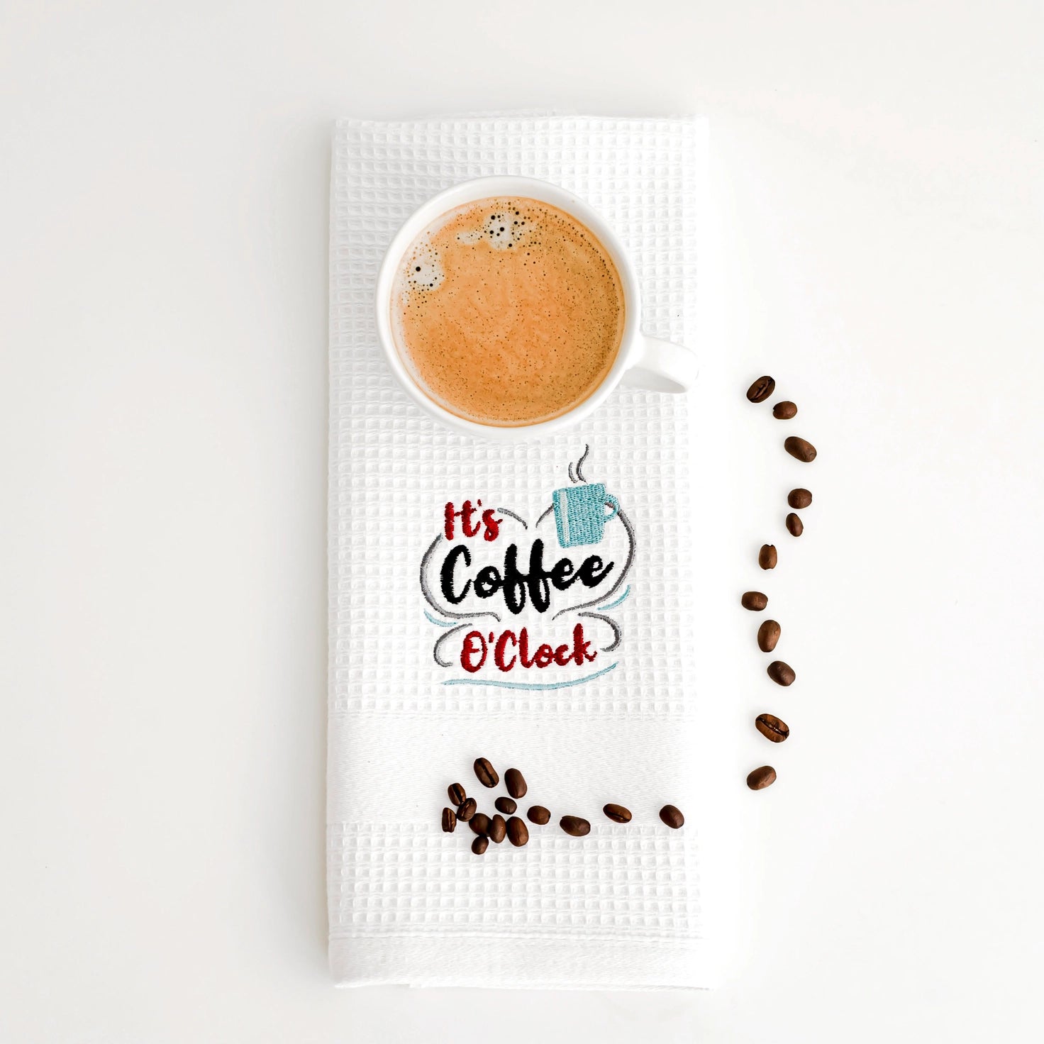 Tea towel with a cup of coffee design and text 'It's Coffee O'Clock' on a white background.
