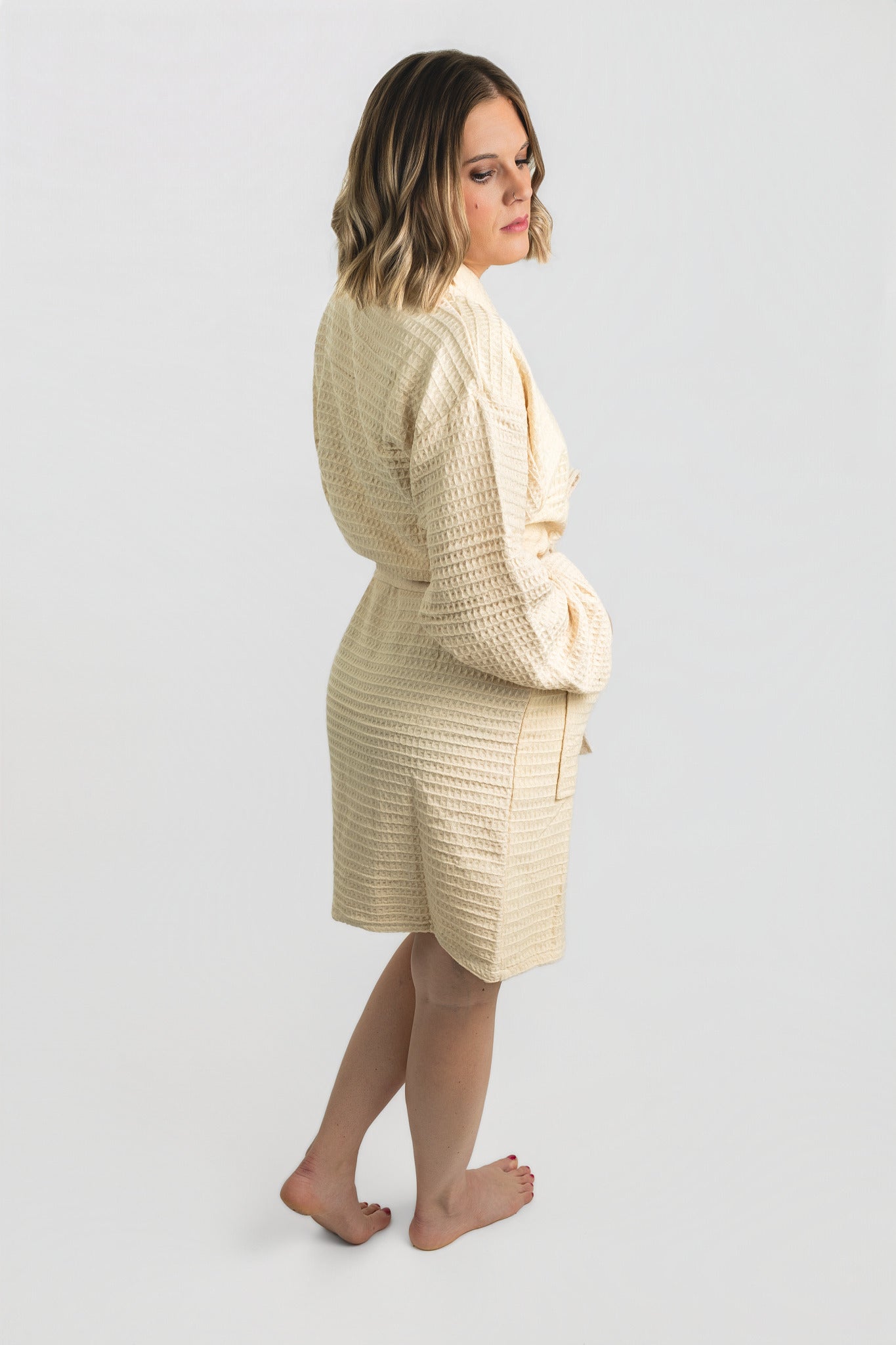 Woman wearing a beige textured robe on a white background