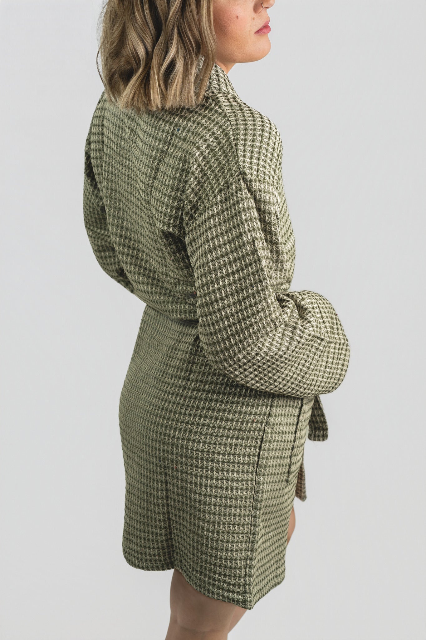Person wearing a green checkered bathrobe with a white background