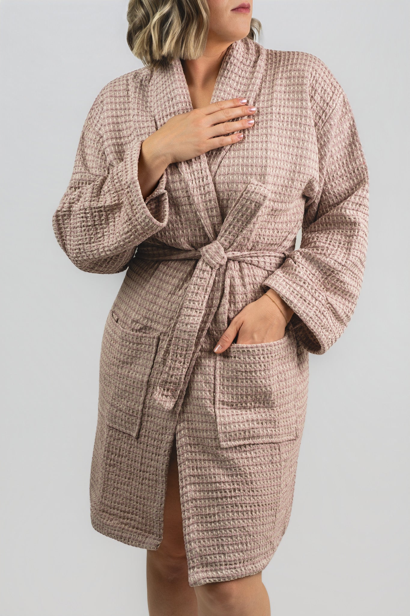 Person wearing a textured pink robe against a plain background