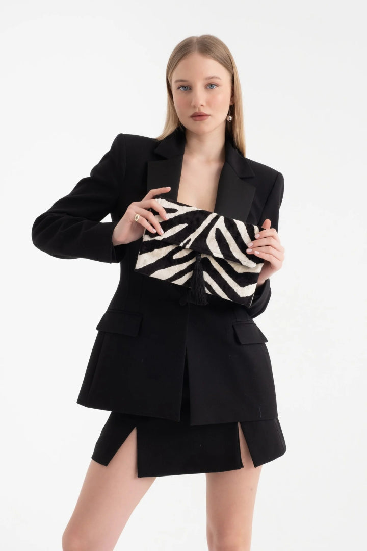 Model in a black blazer holding the Midnight Zebra silk velvet clutch
