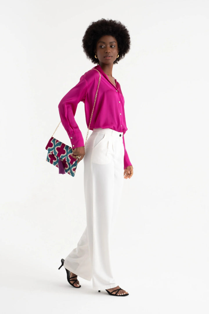 The teal and magenta quatrefoil silk velvet clutch carried by its tassel