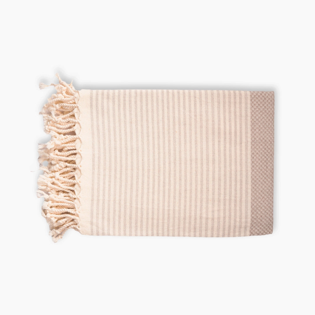 Beige waffle weave peshtemal towel folded, with hand-knotted fringe