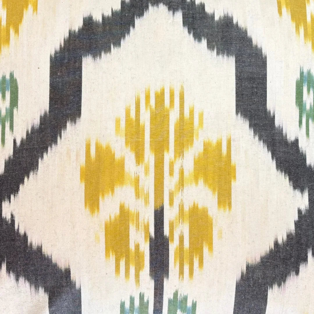 Close-up of a saffron ikat bloom inside its charcoal ogee frame