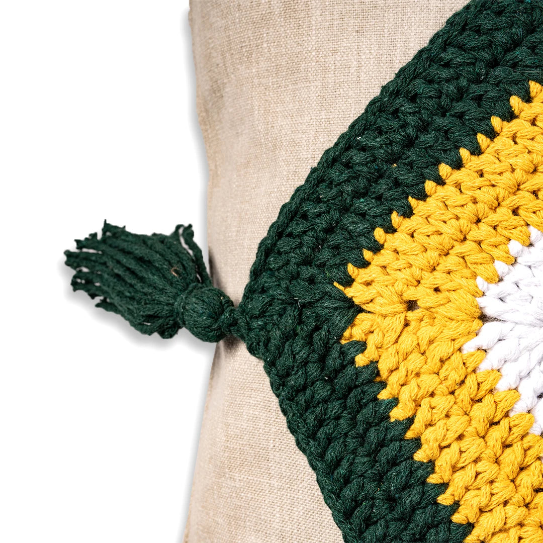 Close-up of the green crochet trim and knotted tassel on the linen evil eye cushion