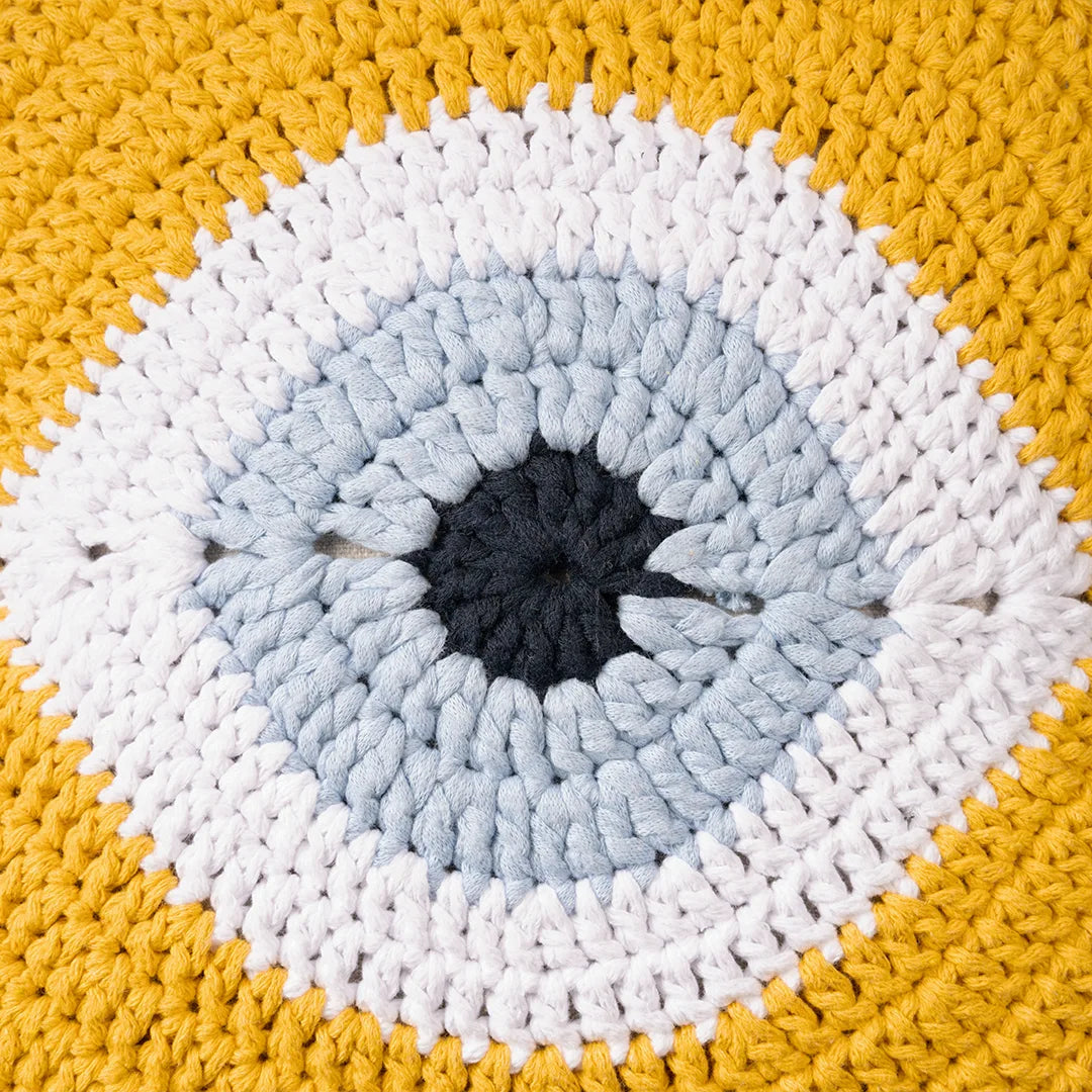 Close-up of the yellow crocheted evil eye motif with its pale blue iris