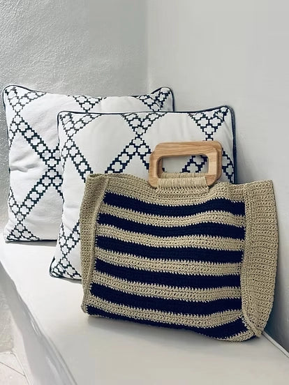 Carole crochet raffia tote styled on a cream sofa beside patterned cushions