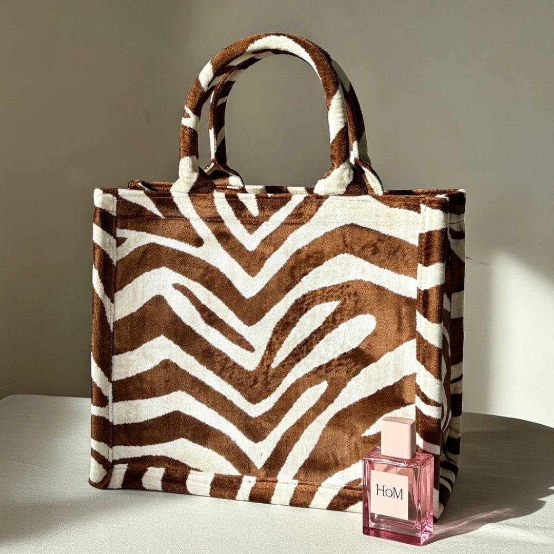 Desert Zebra brown and ivory silk velvet tote bag styled in soft daylight beside a House of Motifs perfume bottle