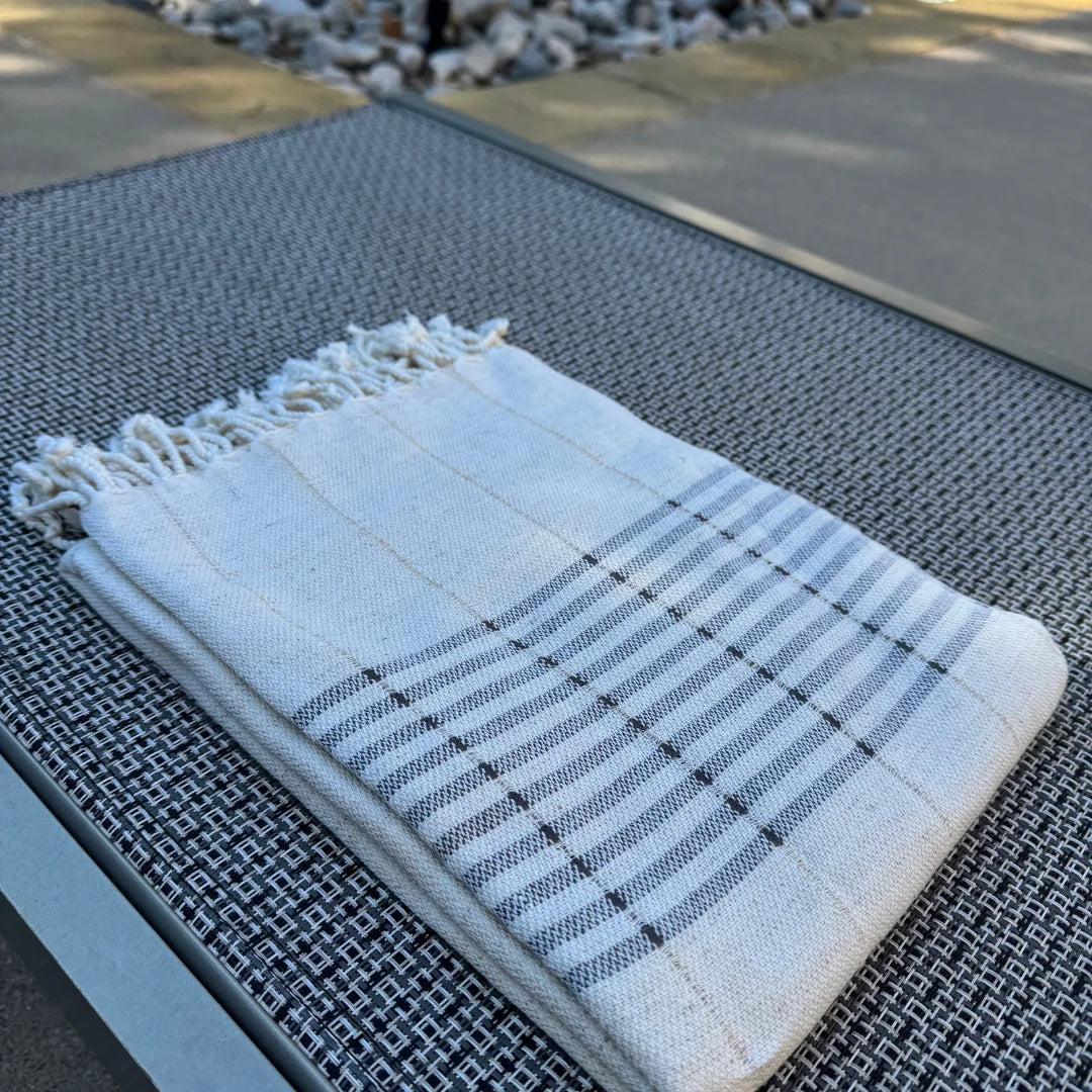 White towel with black stripes and fringes on a textured surface