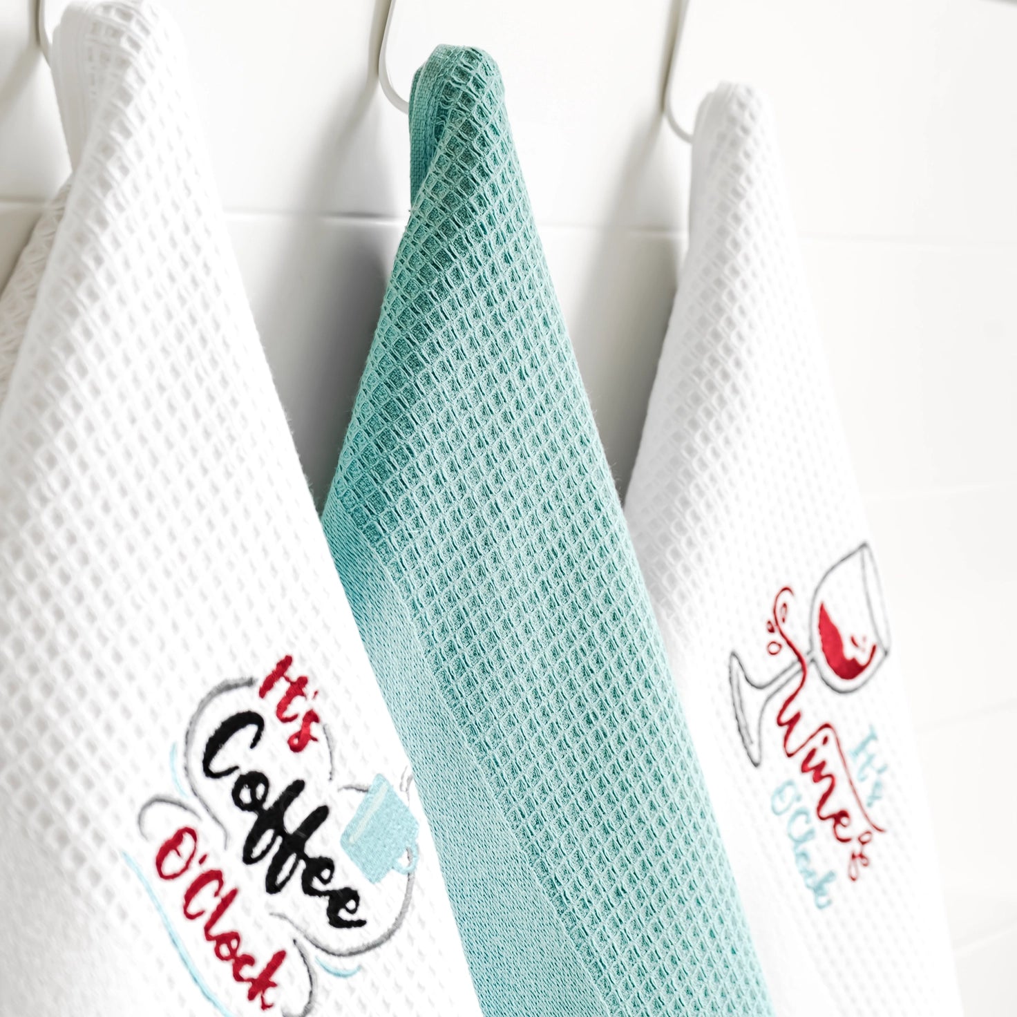 Set of three kitchen towels with text designs on a white background