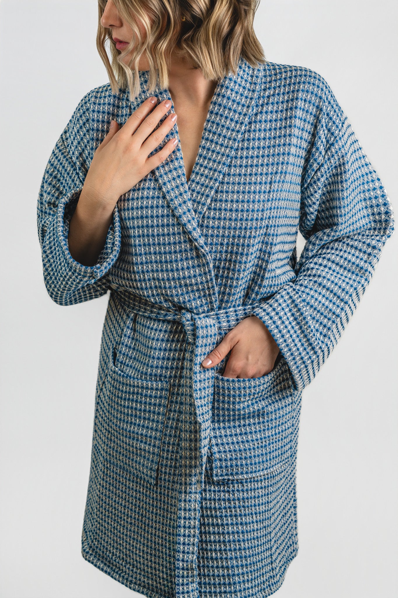 Person wearing a blue and white checkered robe against a white background
