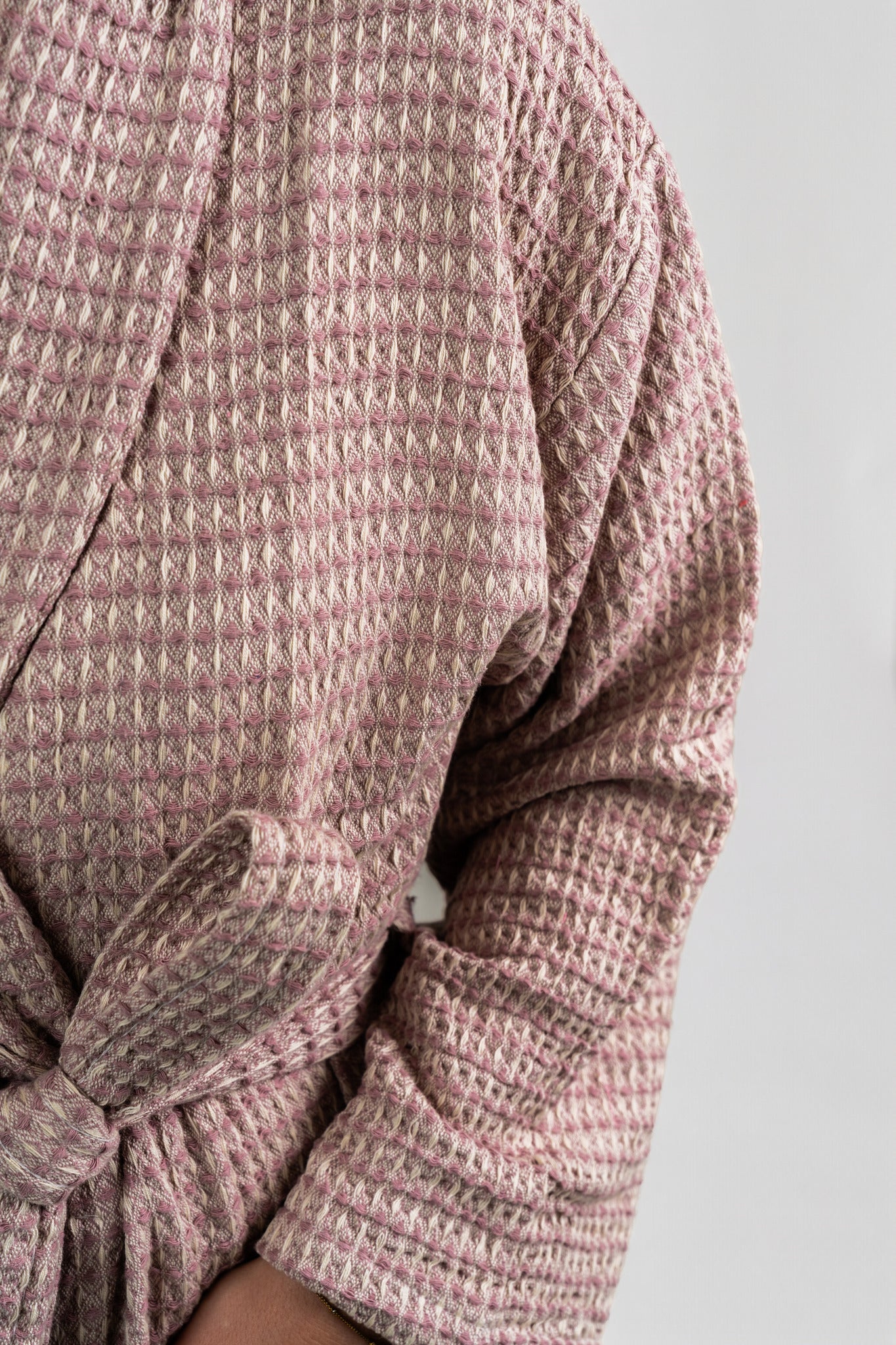 Close-up of a textured pink robe with a tie waist on a light gray background