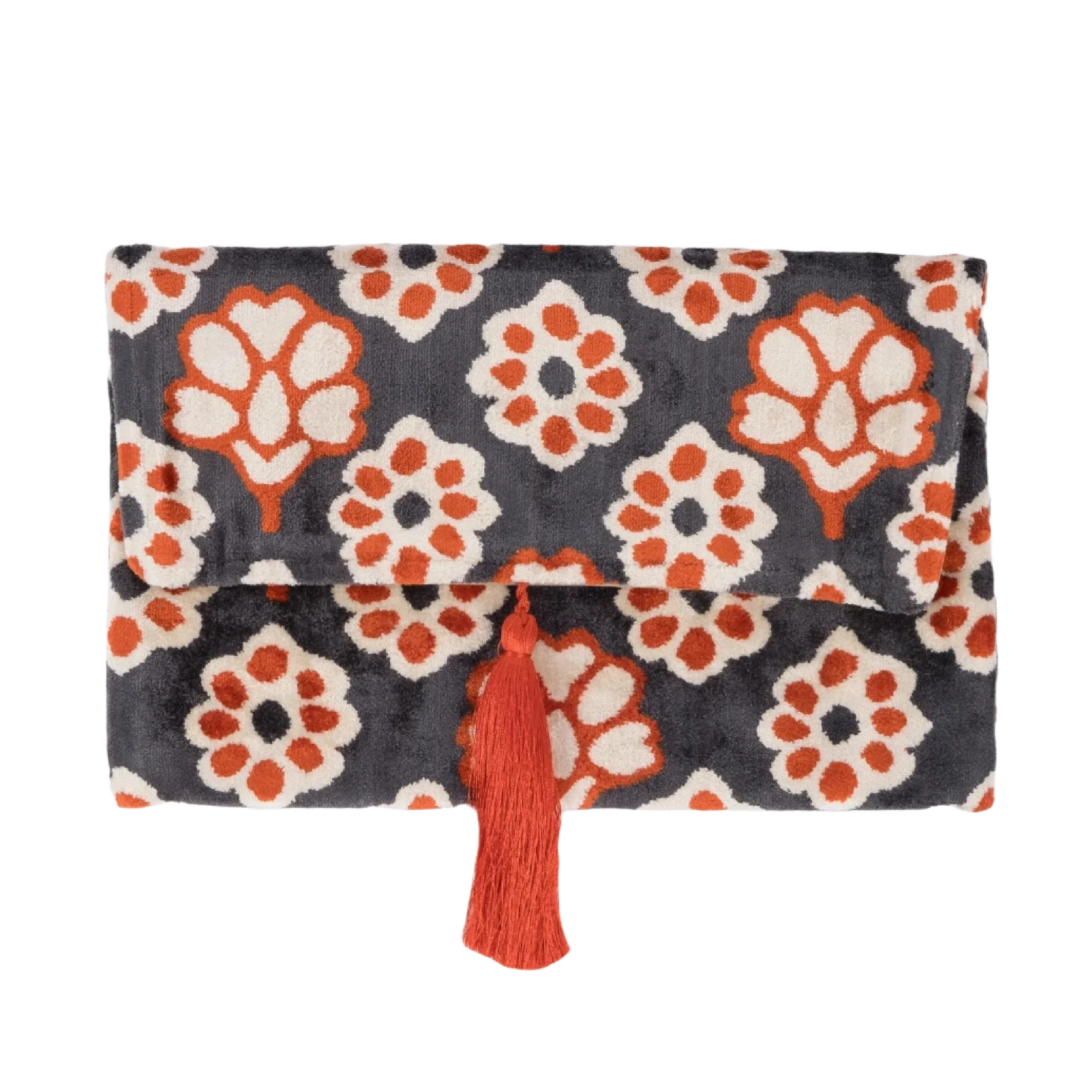 Coral and orange carnation blooms on an anthracite silk velvet clutch with a matching tassel