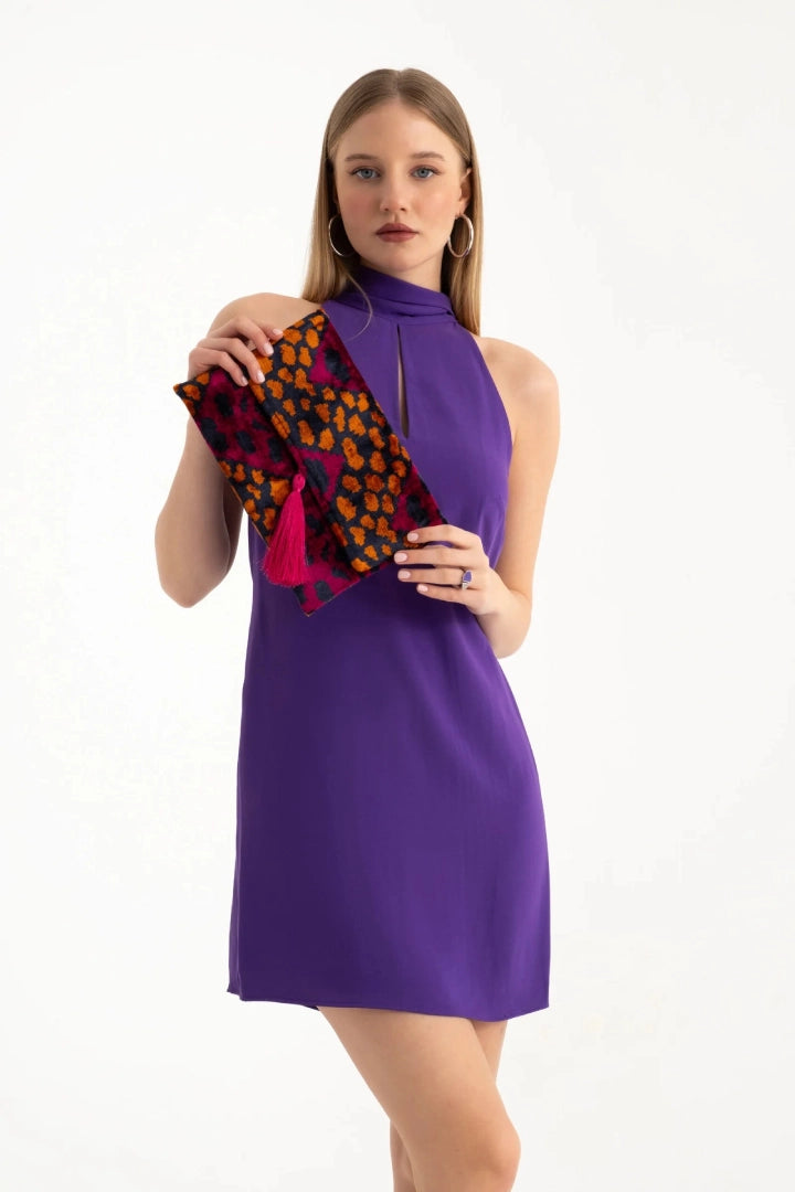 Model in a purple dress holding the berry leopard silk velvet clutch