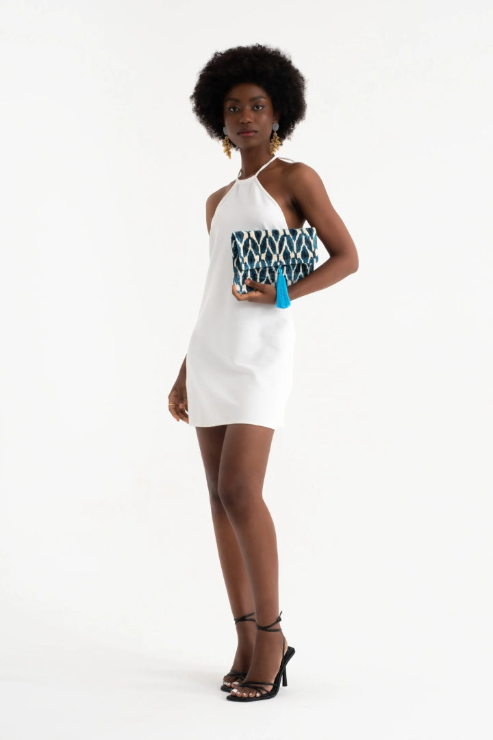 Model in a white dress holding the Midnight Rana Petal silk velvet clutch