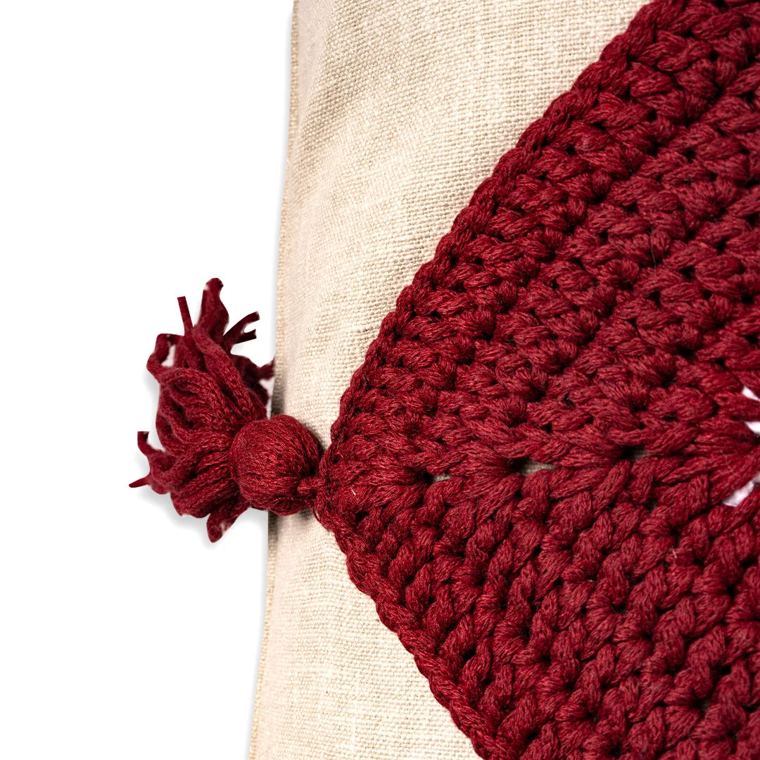 Close-up of the burgundy crochet trim and knotted tassel on the linen evil eye cushion