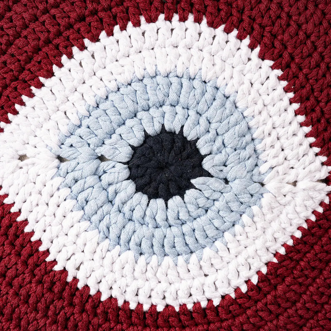Close-up of the burgundy crocheted evil eye motif with its pale blue iris