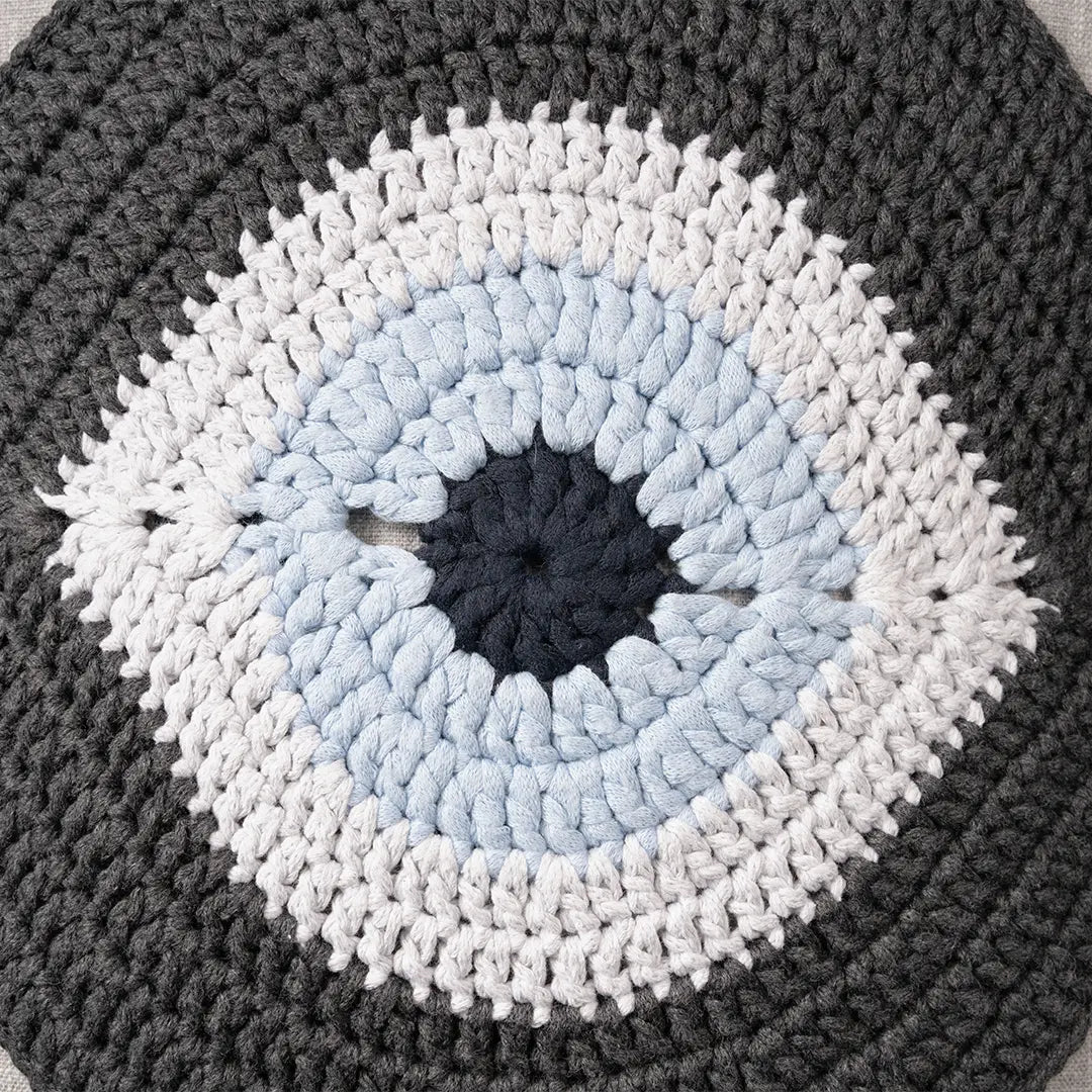 Close-up of the charcoal crocheted evil eye motif with its pale blue iris