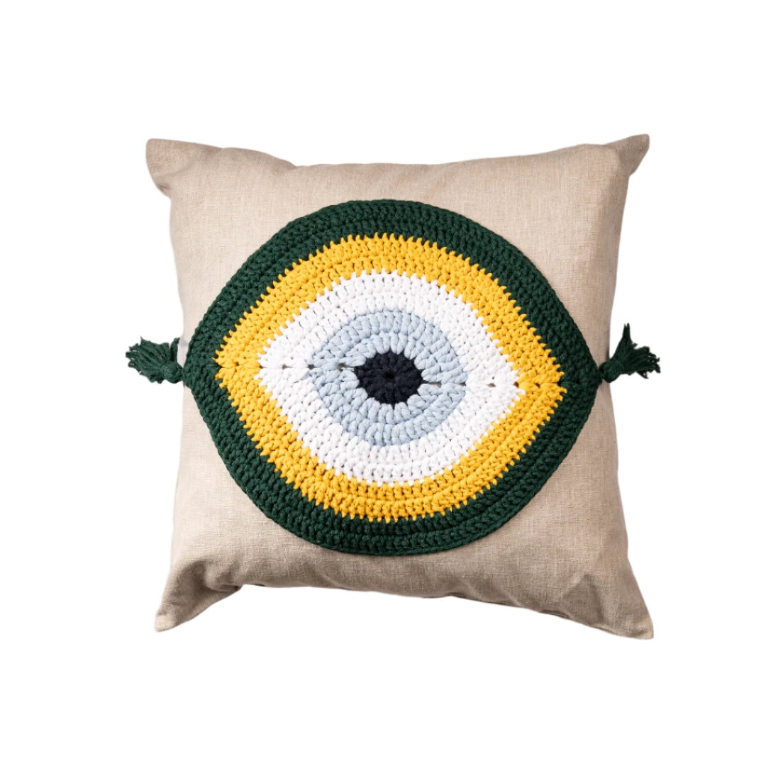 Natural linen cushion with a green and gold crocheted evil eye and corner tassels