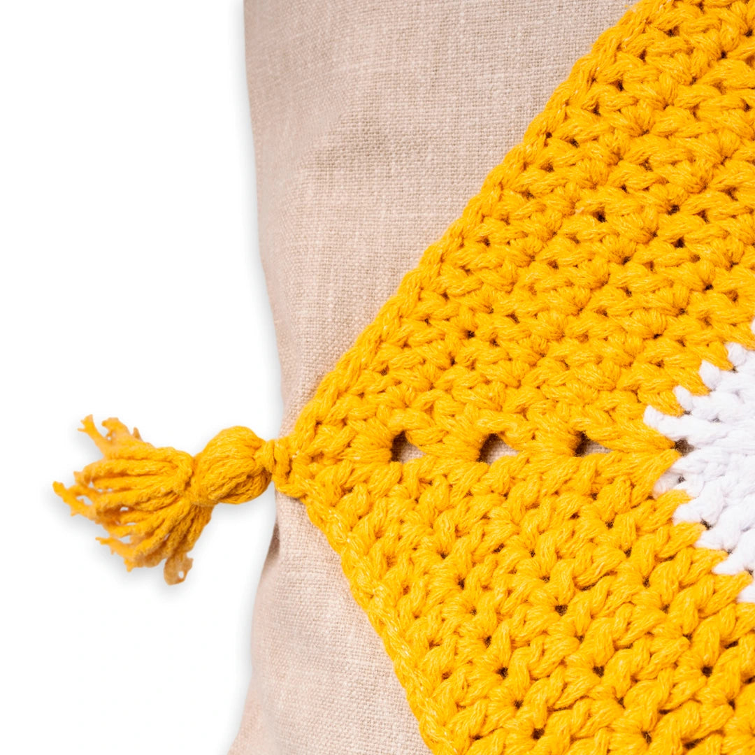 Close-up of the yellow crochet trim and knotted tassel on the linen evil eye cushion