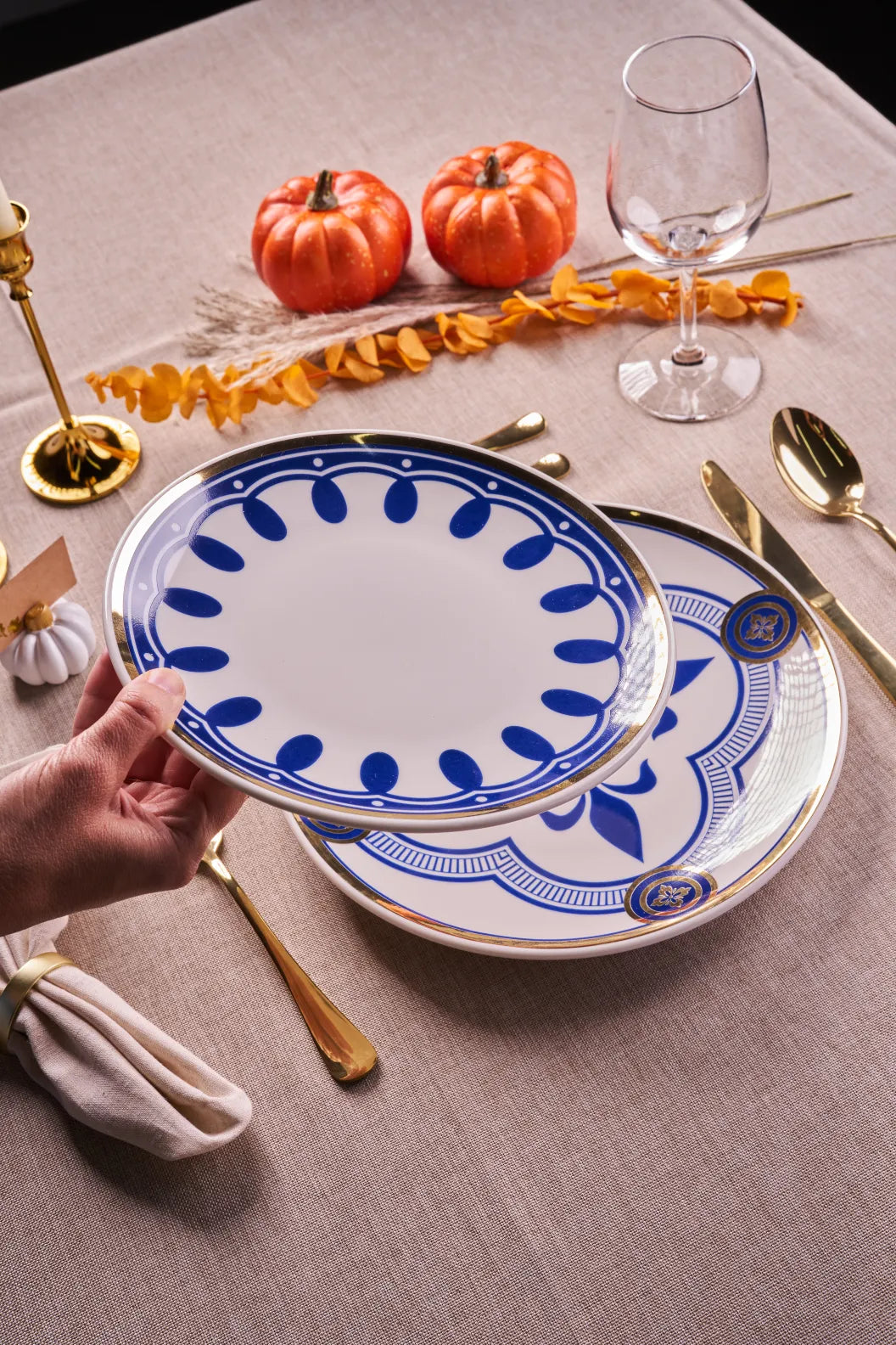 Thanksgiving table with a Myth Mia blue-border salad plate layered on a Myth Orient dinner plate, pumpkins and gold flatware