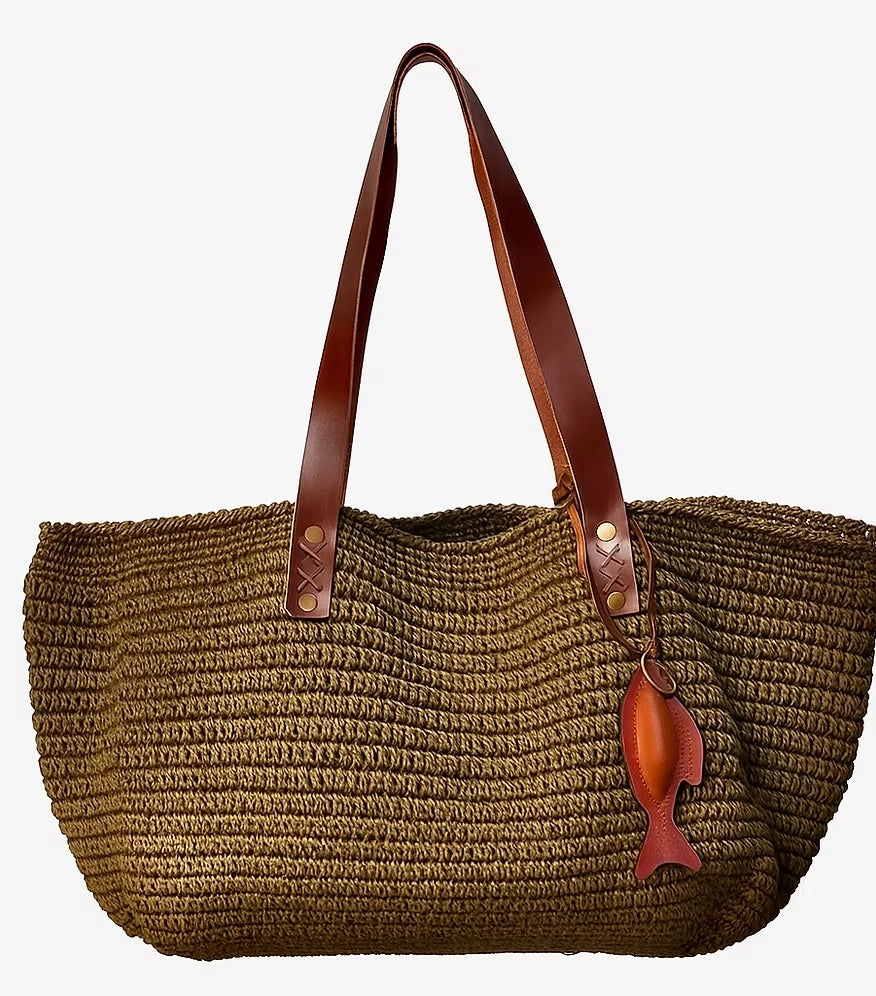 Olive green handwoven raffia basket tote with tan leather handles, front view